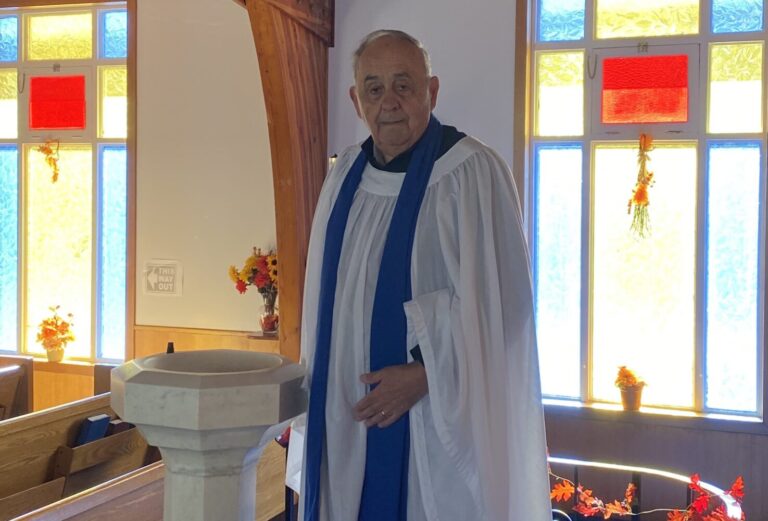 Man in cassock and surplice beside font