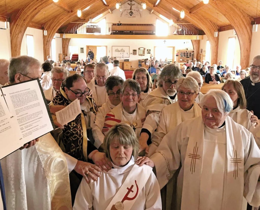 priests and bishop surround woman about to be ordained