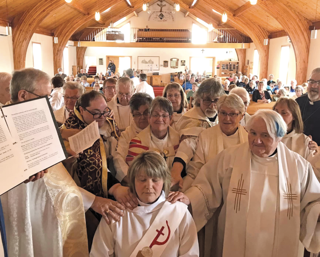 priests and bishop surround woman about to be ordained