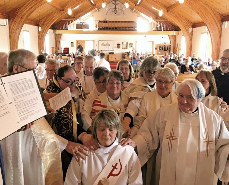 priests and bishop surround woman about to be ordained
