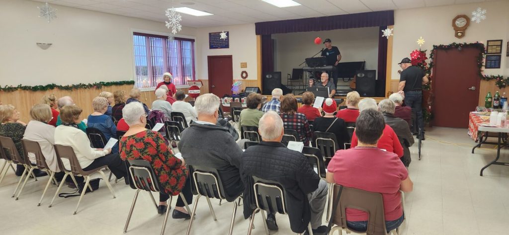 senior citizens gathered to enjoy a show in Bay Roberts Newfoundland with one person playing a kepboard and another singing.