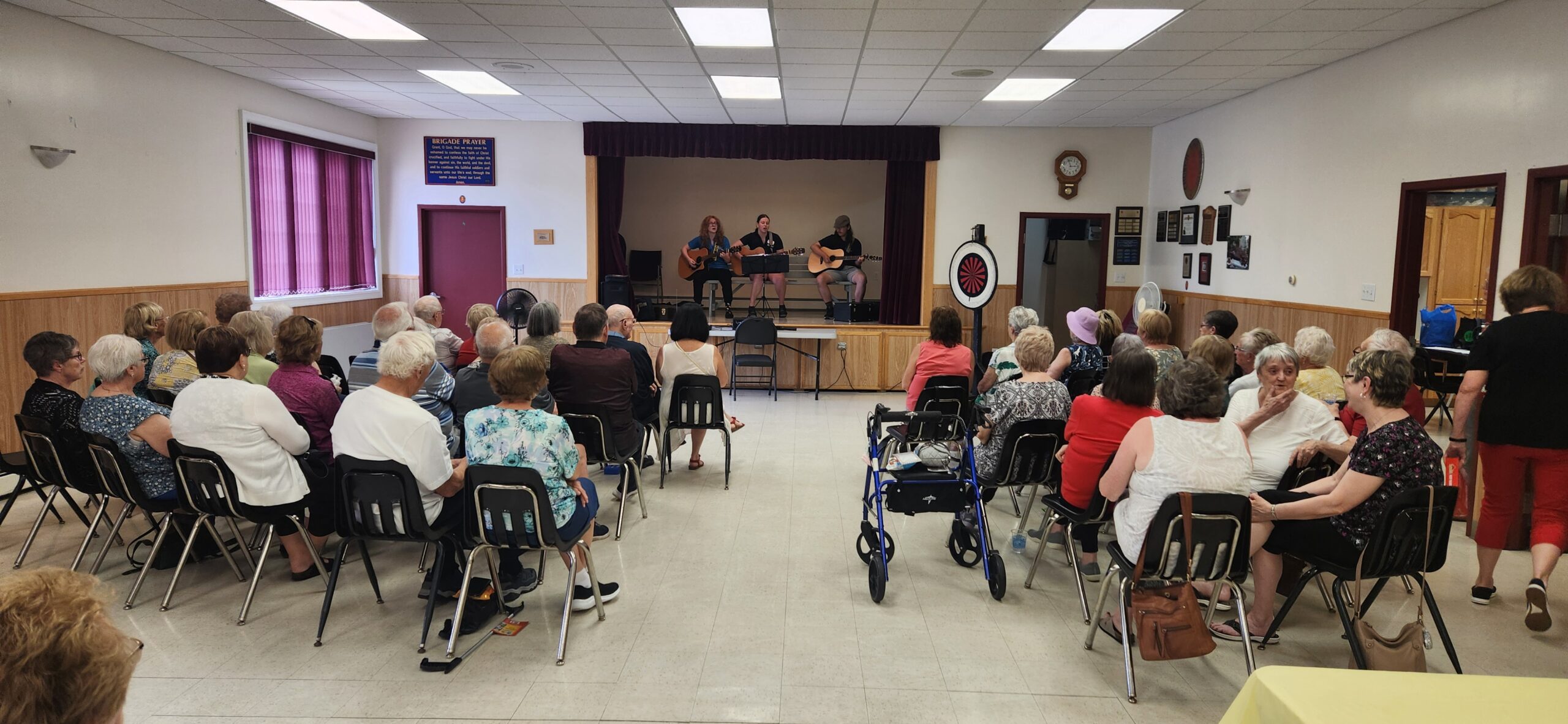 senior citizens gathered to enjoy a show in Bay Roberts Newfoundland with three people playing guitar on stage.