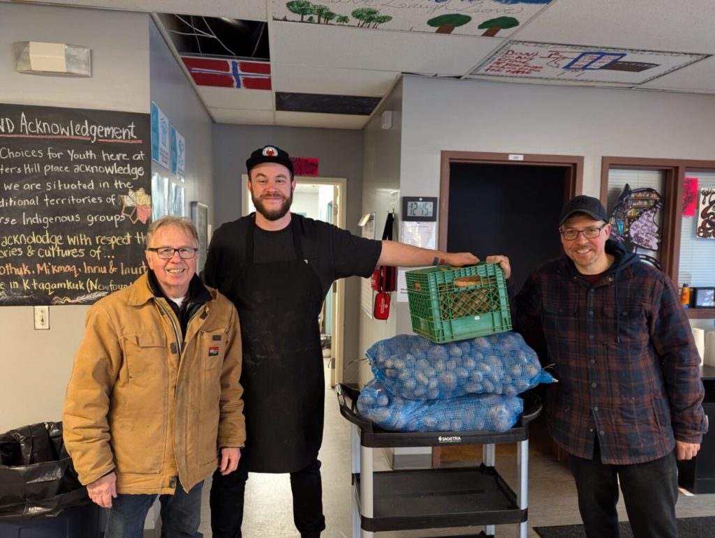 three men making a donation to a food bank