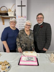 one man and two women prepare to cut a cake to celebrate 75 years of the ACW in Topsail Newfoundland 