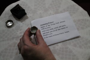 hand holding holy oil next to a prayer card