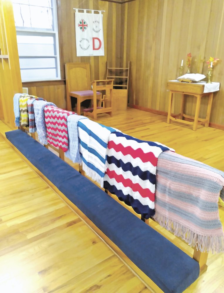 crocheted shawls on wooden rail in church