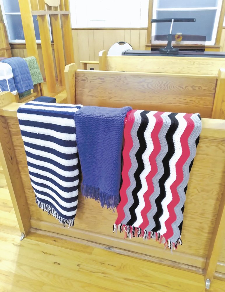 three crocheted blankets on a wooden pew