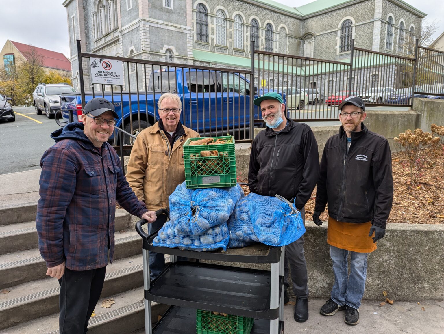 four men in front of the Basilica in St. John's NL making a donation to a food bank