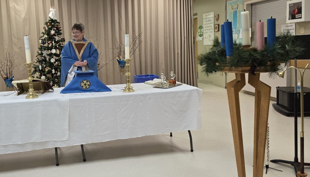 woman behind a table that has been made into an altar with an advent wreath in the foreground