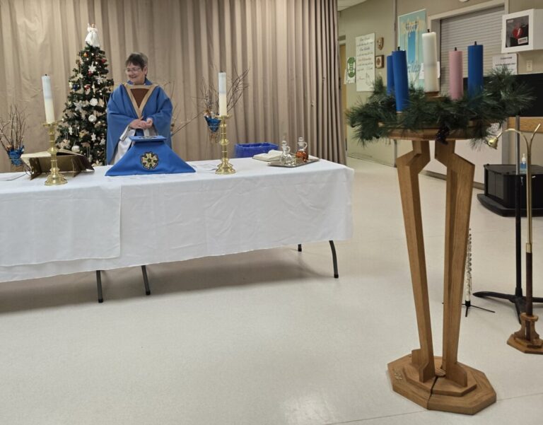 woman behind a table that has been made into an altar with an advent wreath in the foreground