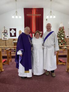 Three people stand in church vestments at the front of St. Paul's, Summerside, NL