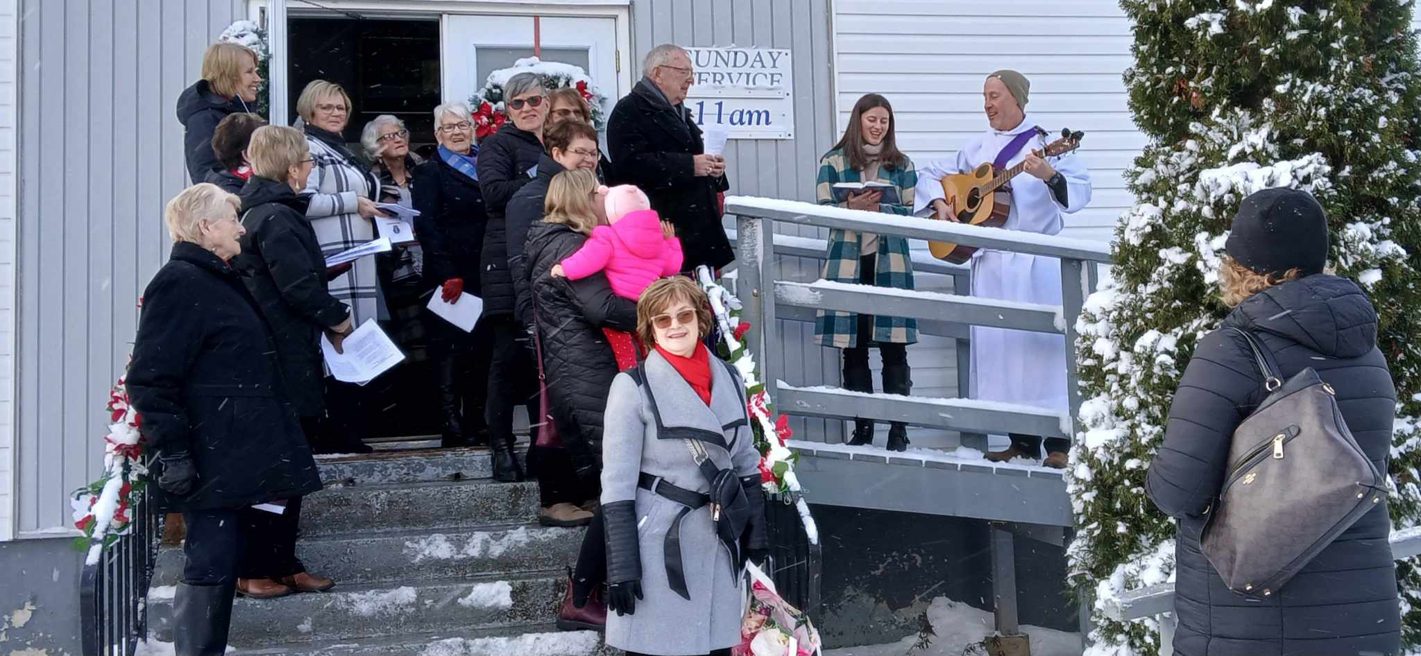 people gathered outside a church to light a christmas tree in memoriy of loved ones