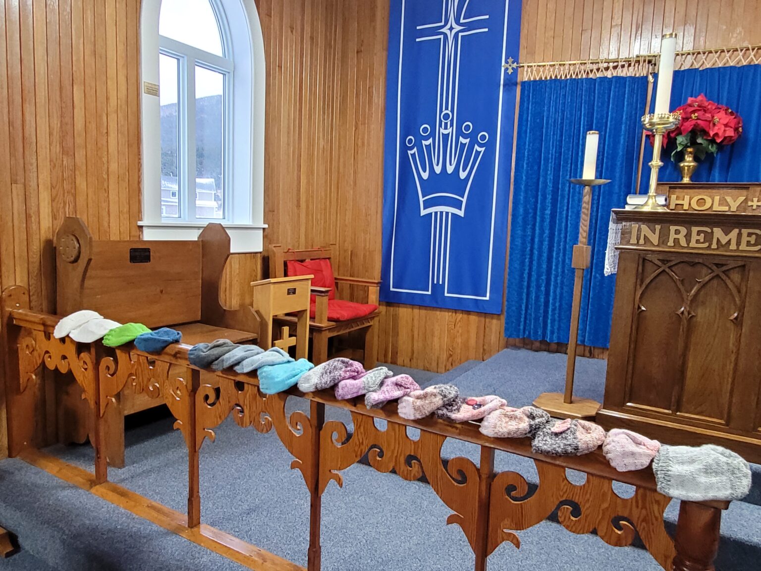 knitted and crocheted caps, made for chemo patients, lined up along a communion rail in a church