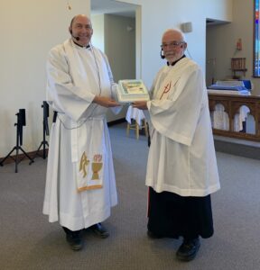 two members of the Anglican clergy pose for a photograph with a cake in a church