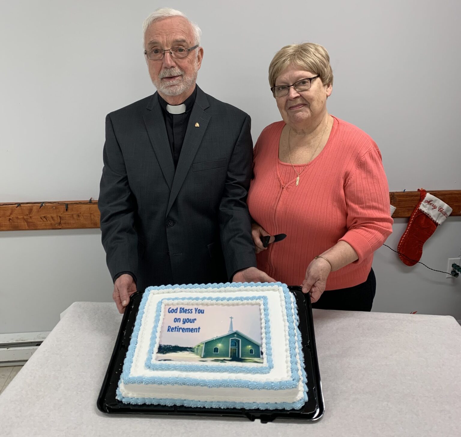 An Anglican priest and his wife pose with his retirement cake