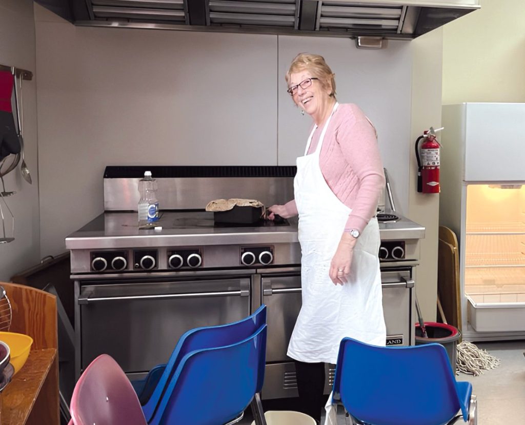 a woman at an industrial stove in a hall, cooking a meal