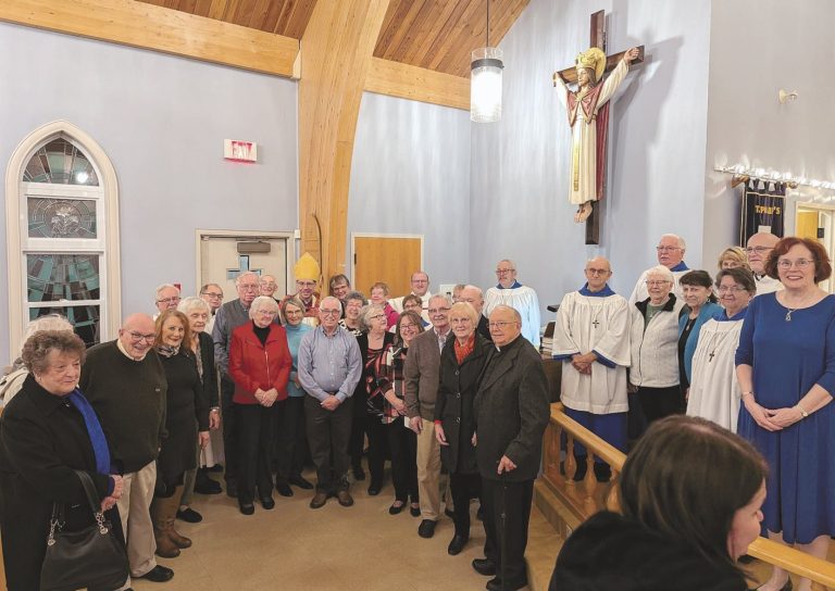 a group of people stand below a statue of Jesus on a wall in a church