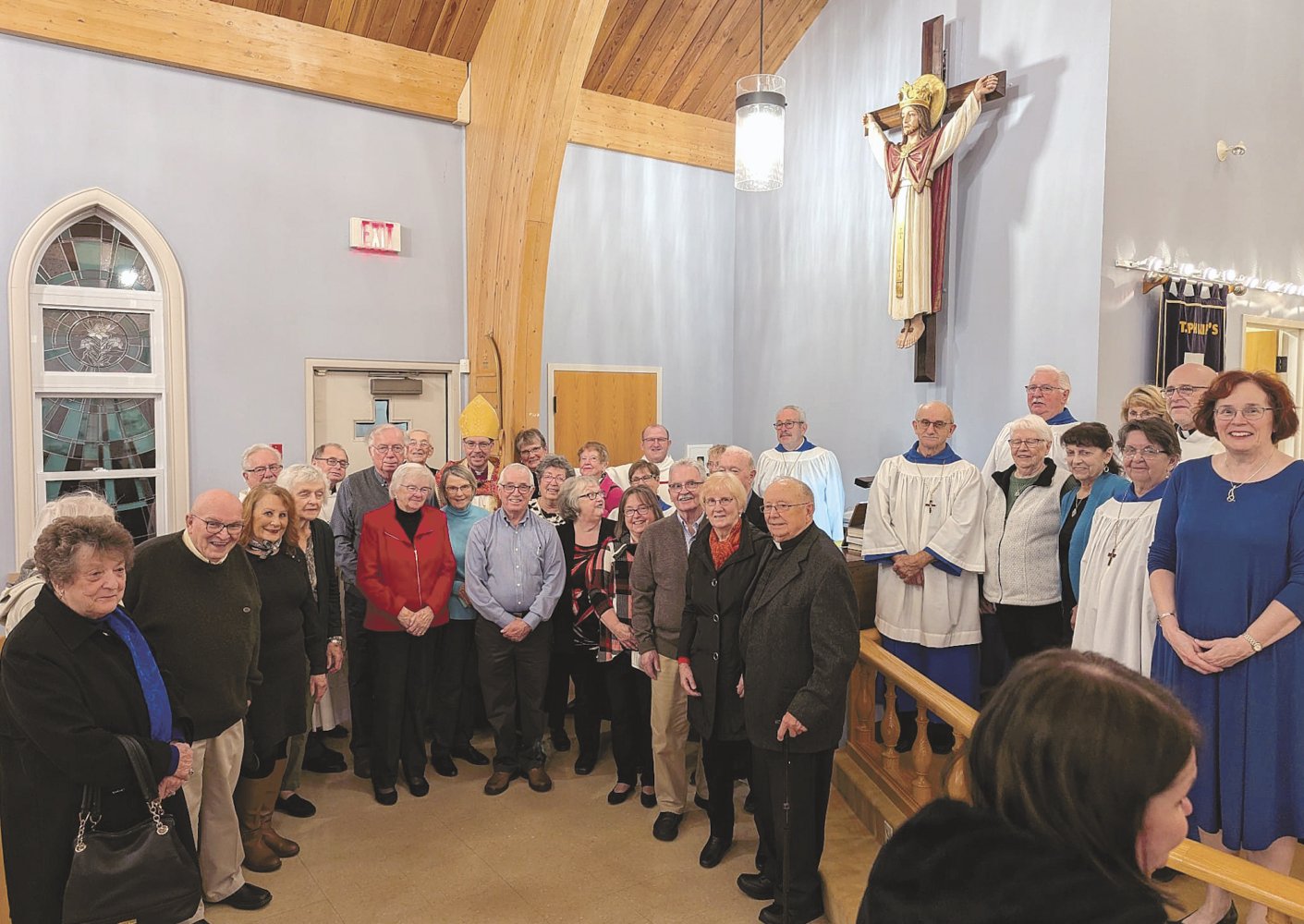 a group of people stand below a statue of Jesus on a wall in a church