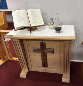 a new credence table in the sactuary of a church with a book on it and wine and water cruets