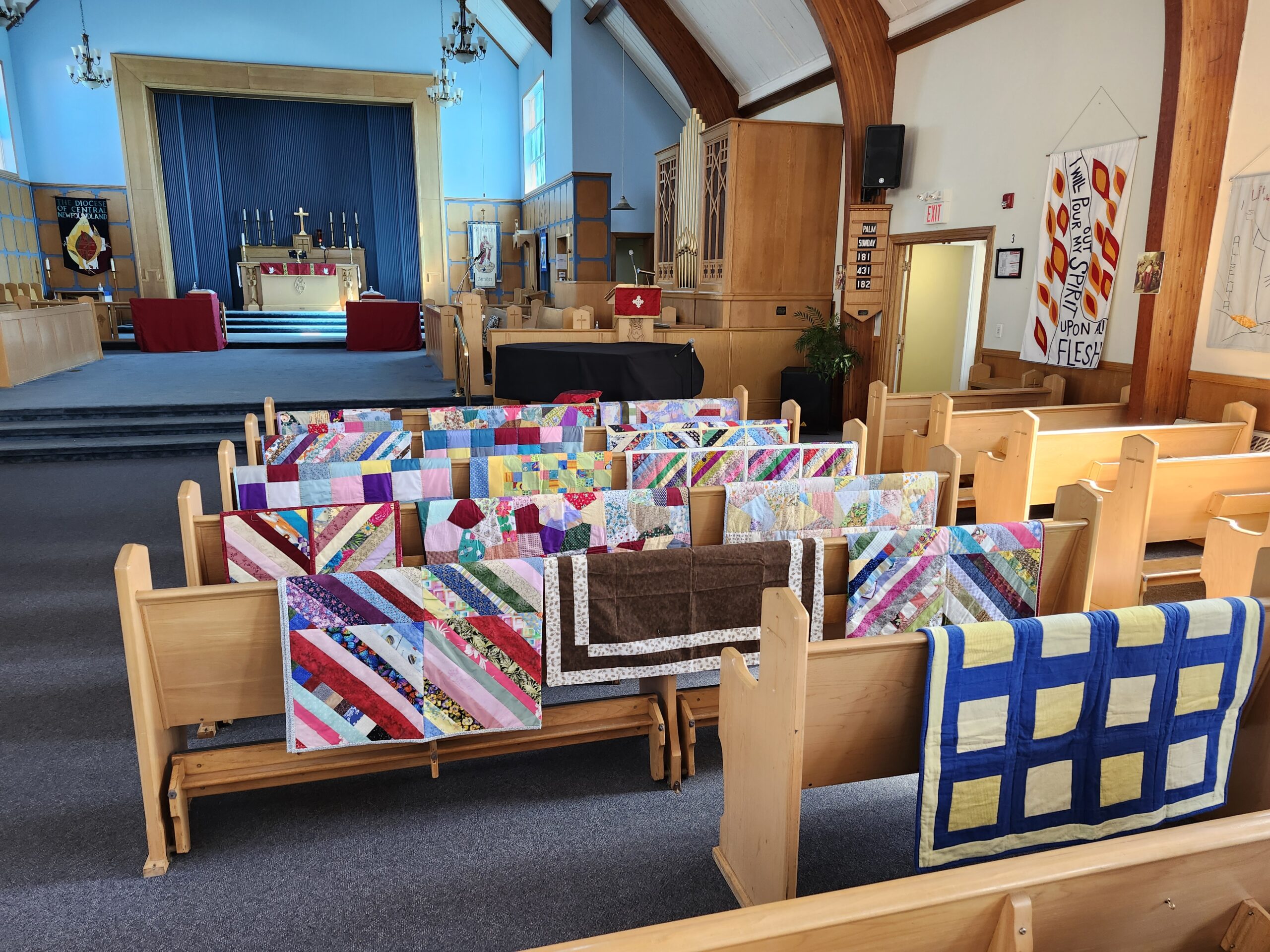 quilts displayed across the backs of pews in a church