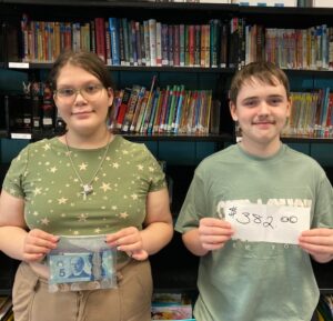 two young people show the money that they have raised to help the Primates World Relief and Development Fund