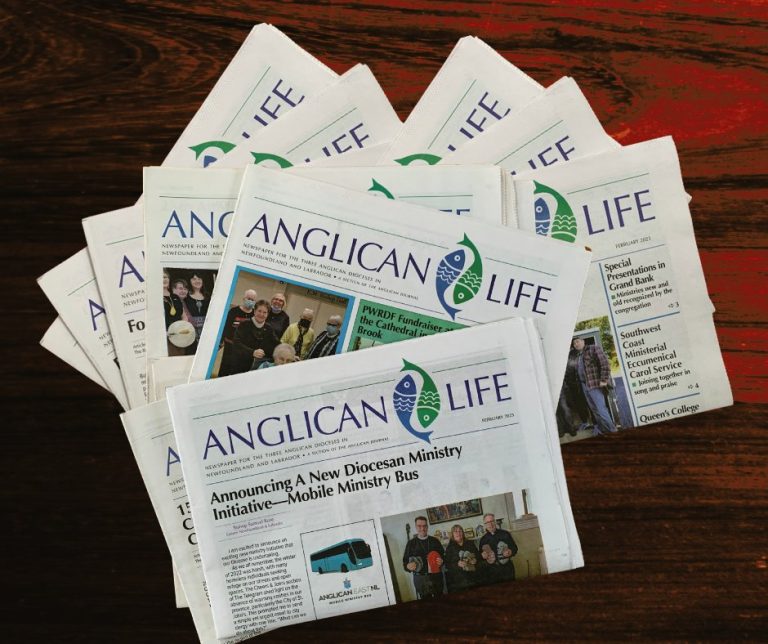 stack of Anglican Life newspapers on a wooden table top