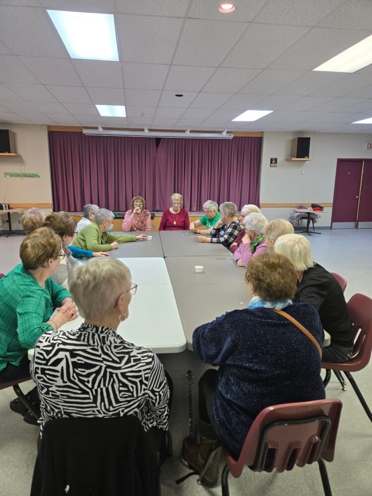 women sitting at folding tables in a church hall