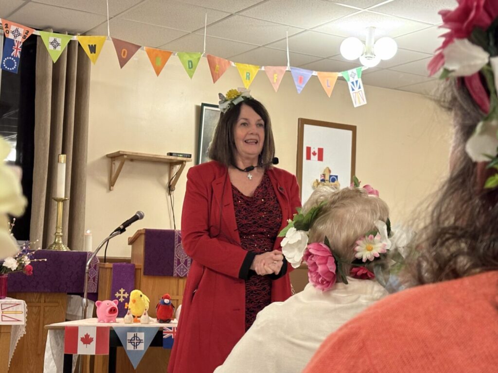 woman speaking to a group of people who are gathered for a World Day of Prayer service