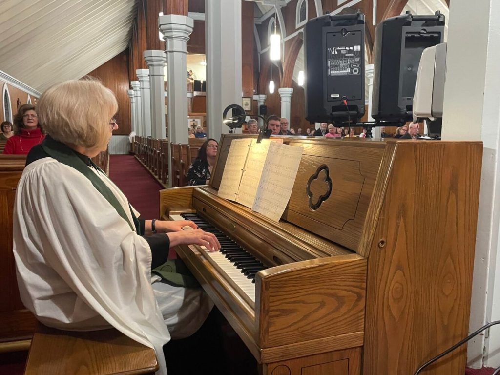 a women, dressed in choir habit, playing a church organ