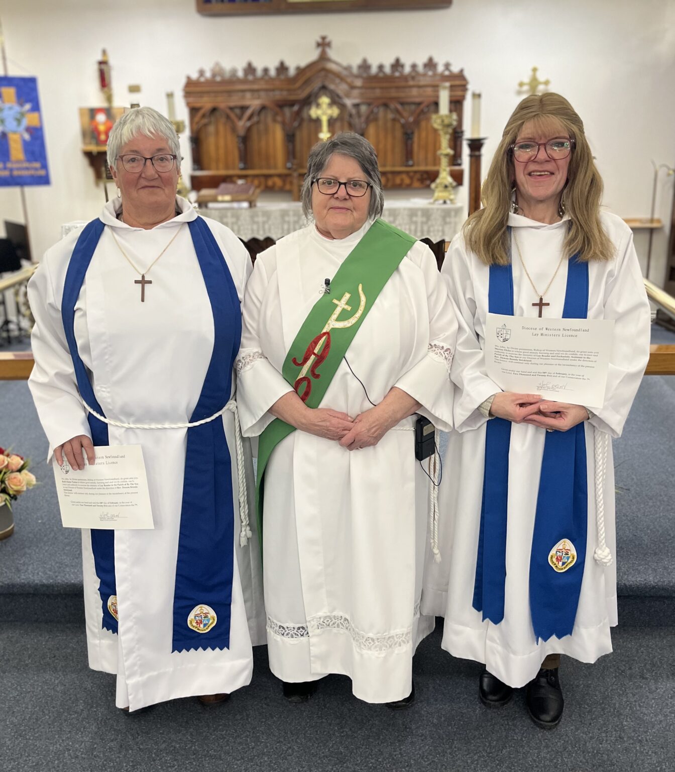 three women,in vestments, stand at the front of a church