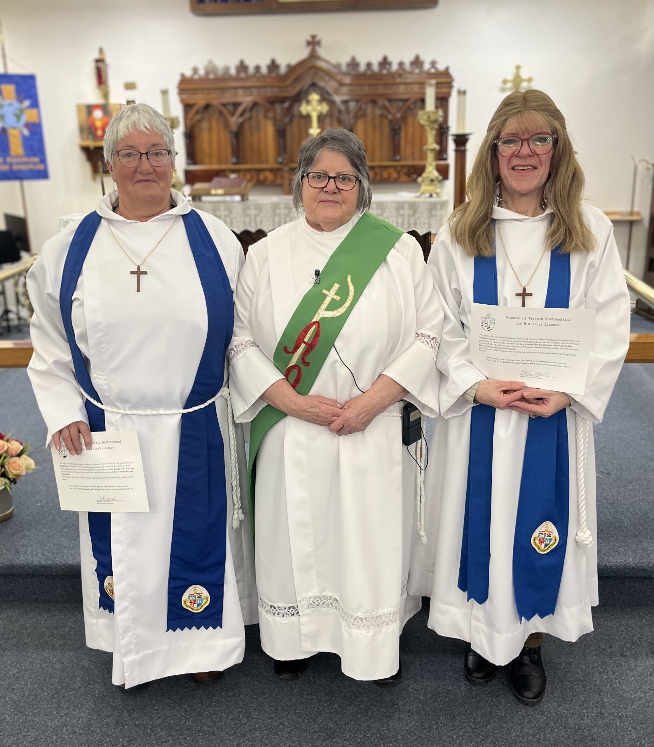 three women,in vestments, stand at the front of a church