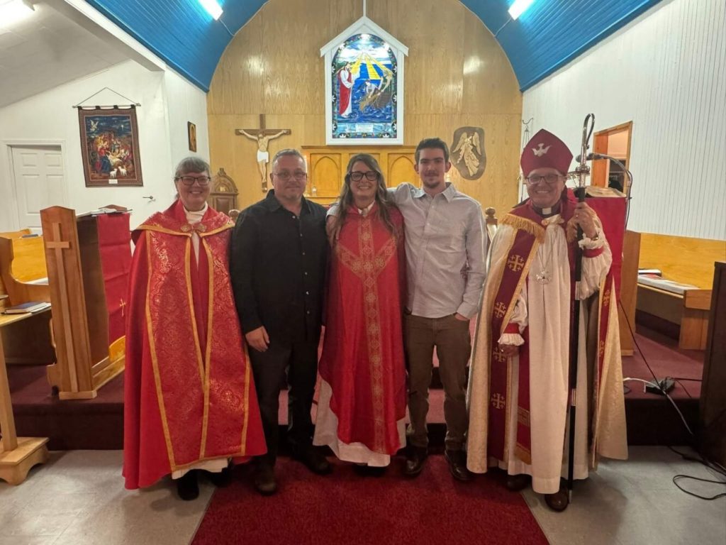 Five people at the front of a church, three dressed as members of the clergy.