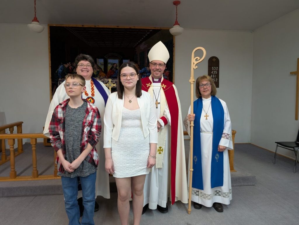 Two young people and two adults dressed as lay readers pose with a man dressed as a Bishop of the Anglican church