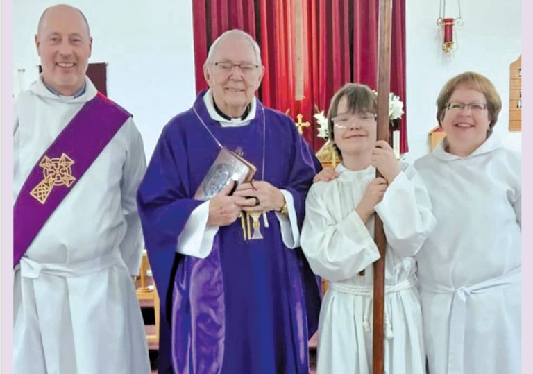 The image shows four people in a church. Two individuals are wearing white robes, one with a purple stole, while another wears a purple robe and holds a book with a cross.