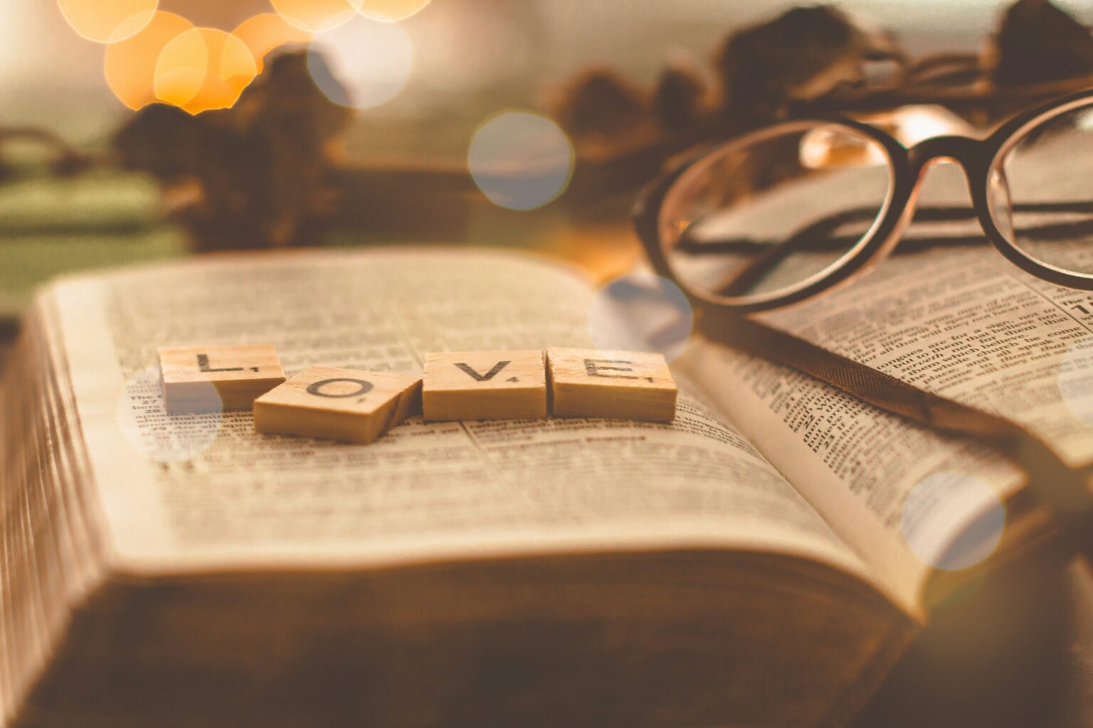 a pair of glasses and scrabble tiles, spelling L-O-V-E, sitting on a Bible