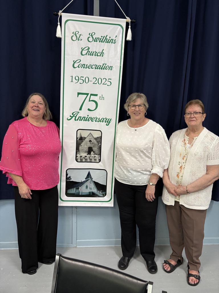 Three women standing next to a banner.