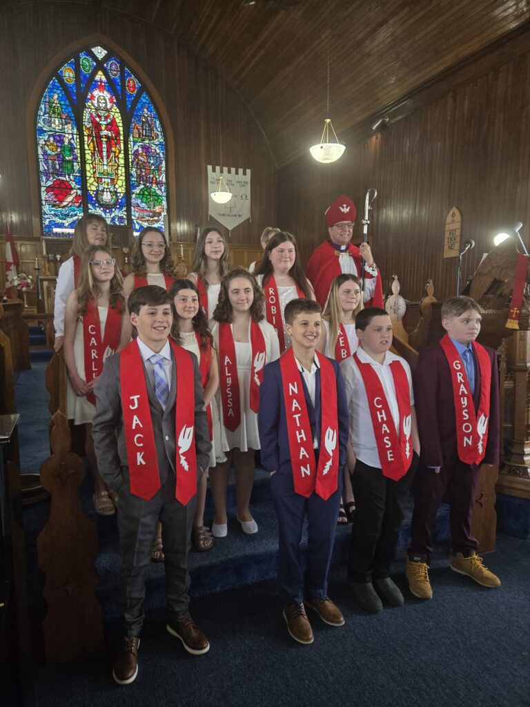 
A group of children and a bishop standing in a church.