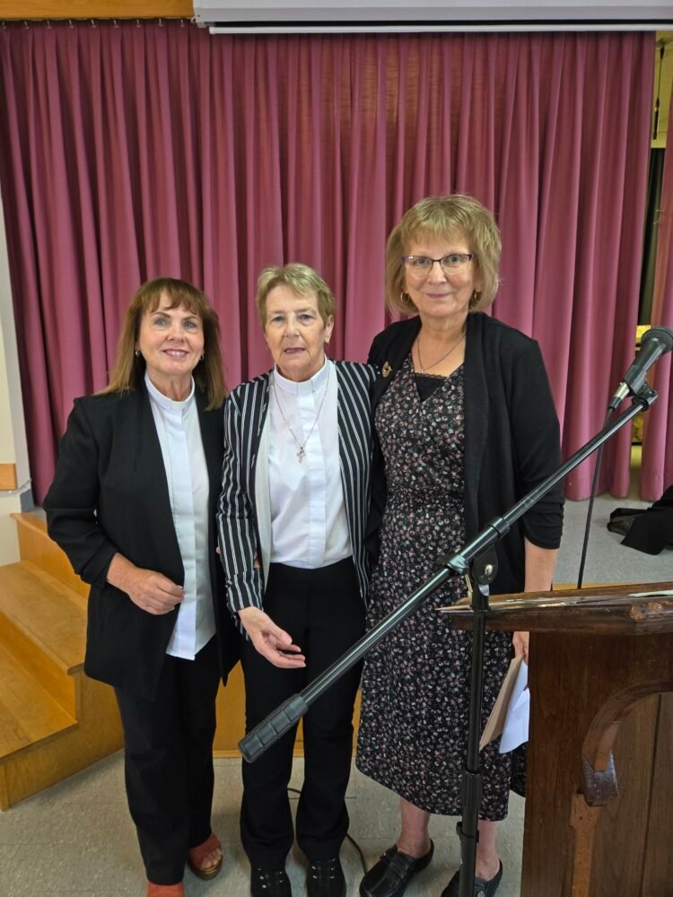 three women, one presenting the other two with gifts