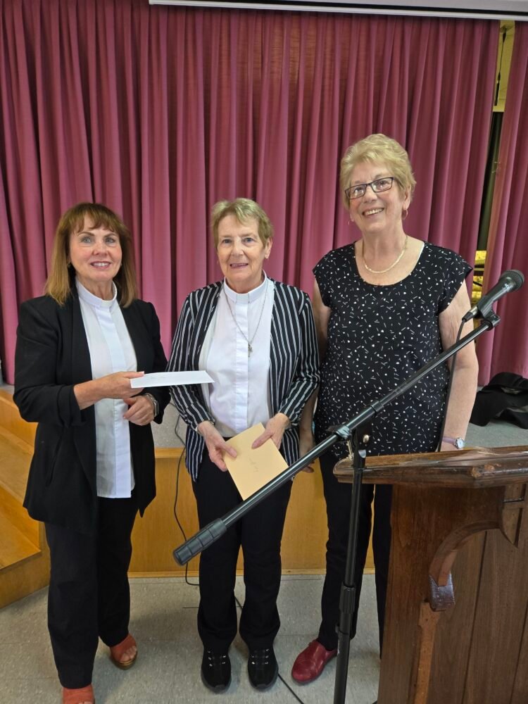 three women, one presenting the other two with fa gift
