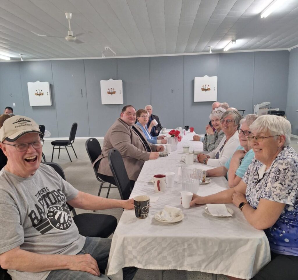A group of people sitting at a long table, talking and laughing.