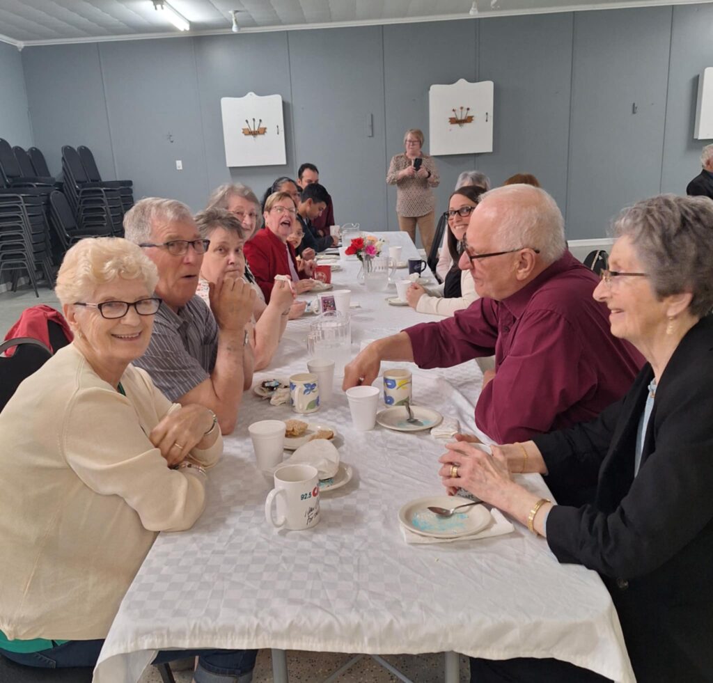 A group of people sitting at a long table, talking and laughing.