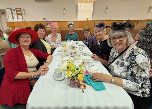 An event with many people seated at tables in a large hall with a decorated stage.