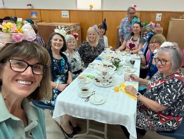 An event with many people seated at tables in a large hall with a decorated stage.