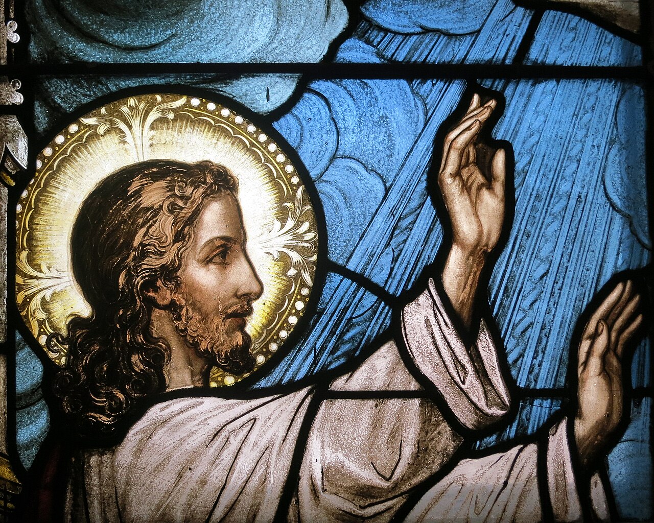 stained glass window of jesus with his hands raised