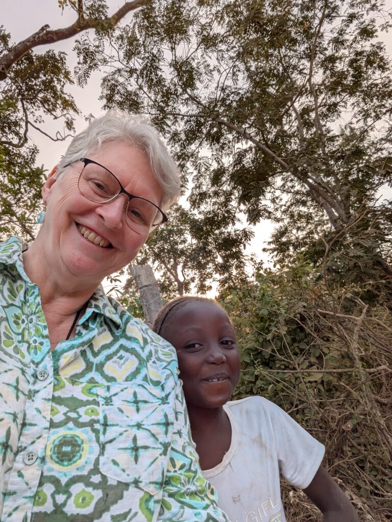 A woman and a child smiling at the camera outdoors.