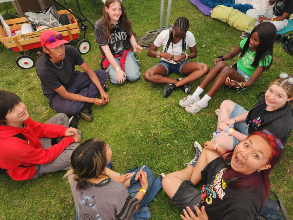 youg people sitting in a circle on green grass