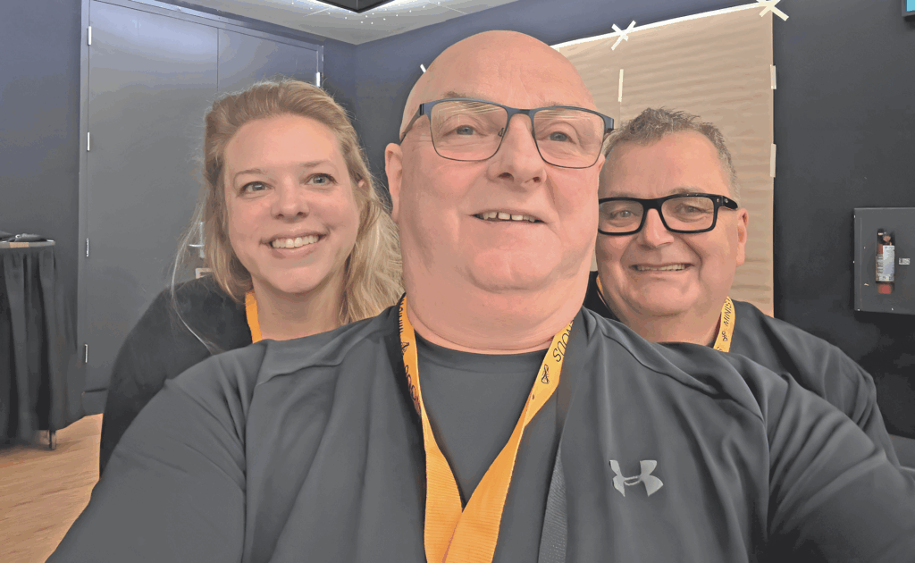 Three people wearing back shirts and orange lanyards
