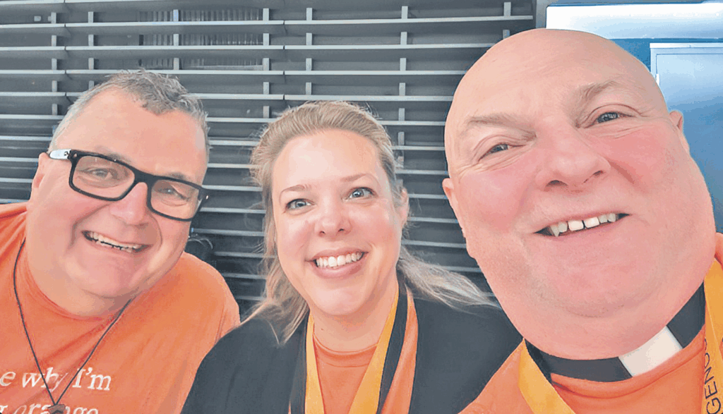 Three people with orange shirts on at a Canadian Indigenous event