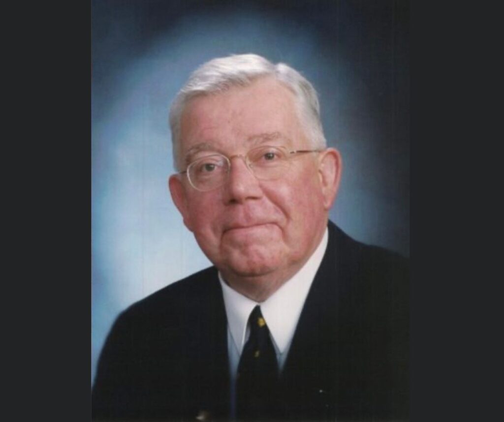 an older man with grey hair, wearing a black suit
