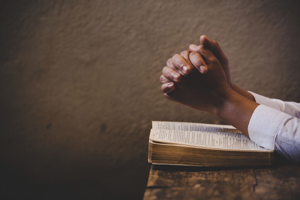 hand folded in prayer resting on a book